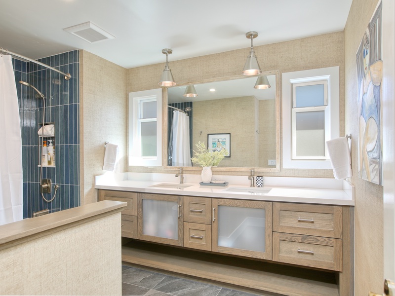 Freshly updated, beach-inspired bathroom with custom cabinetry, a double-sink vanity, and a newly tiled tub and shower combination. Light, airy, and thoughtfully designed to capture a relaxed coastal feel for starting or unwinding after a day by the ocean.