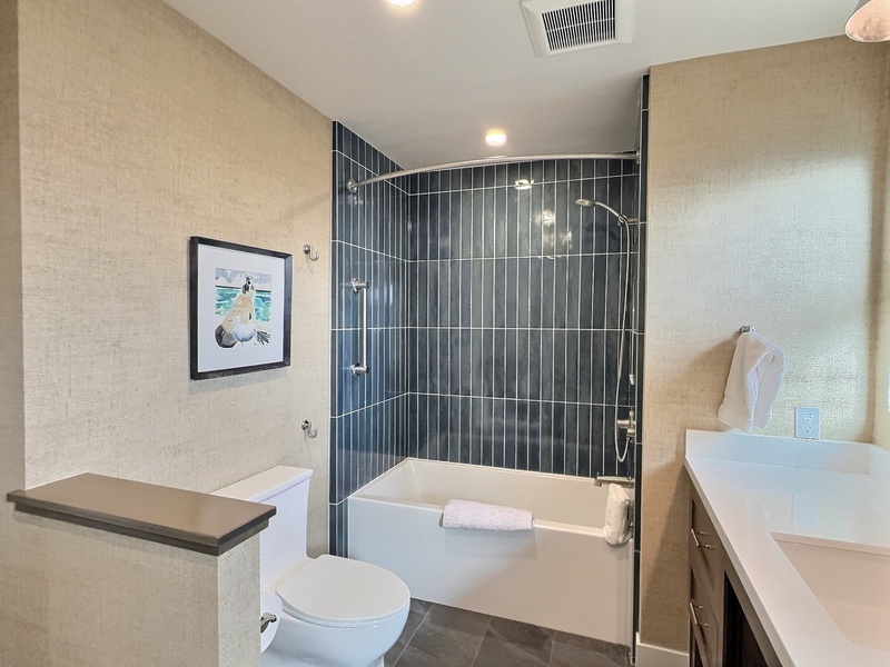 Freshly renovated, beach-inspired bathroom featuring a custom tub and shower finished with vibrant azul-colored tile. Light-filled and airy, this space is designed to capture a relaxed, coastal vibe.