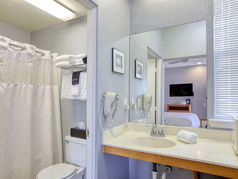 The bathroom comes complete with a tub/shower combo, a vanity, hair dryer, and fresh bath towels—everything you need to refresh after a day at the beach.
