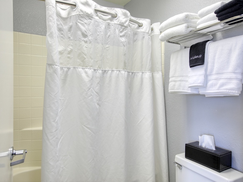 The bathroom includes a tub/shower combination, plush white towels, and complimentary bath soaps for a refreshing start or relaxing end to your day.