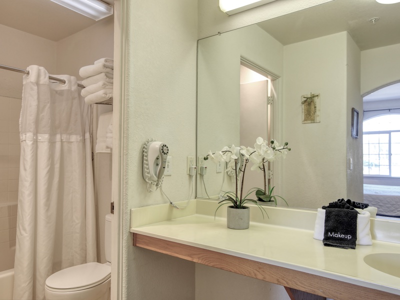 The bathroom includes a tub/shower combination, plush white towels, and complimentary bath soaps for a refreshing start or relaxing end to your day.