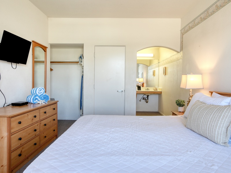 Charming and serene, the bedroom features a king bed dressed in soft white linens, creating a peaceful retreat for a restful night’s sleep.
