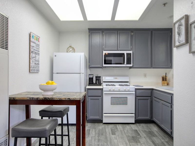 This modern kitchen features sleek gray cabinetry, full-size appliances, and a cozy dining nook for two.