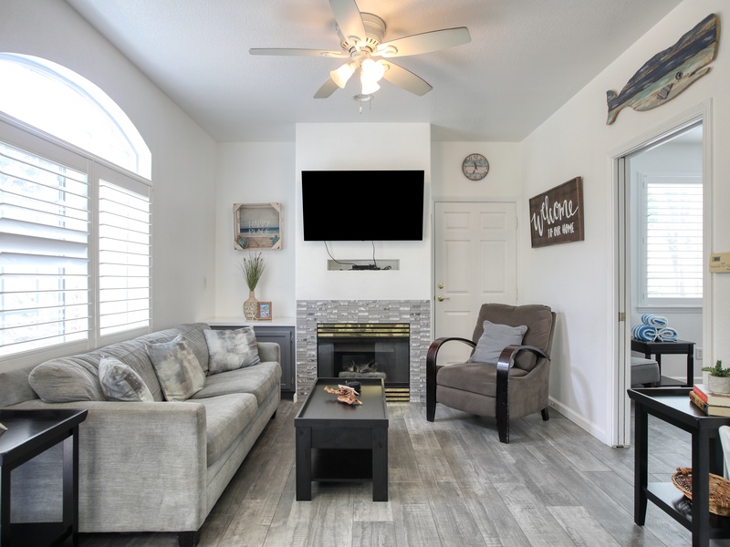 This cozy downstairs unit features a bright living space with modern coastal decor, a fireplace, and plenty of natural light.