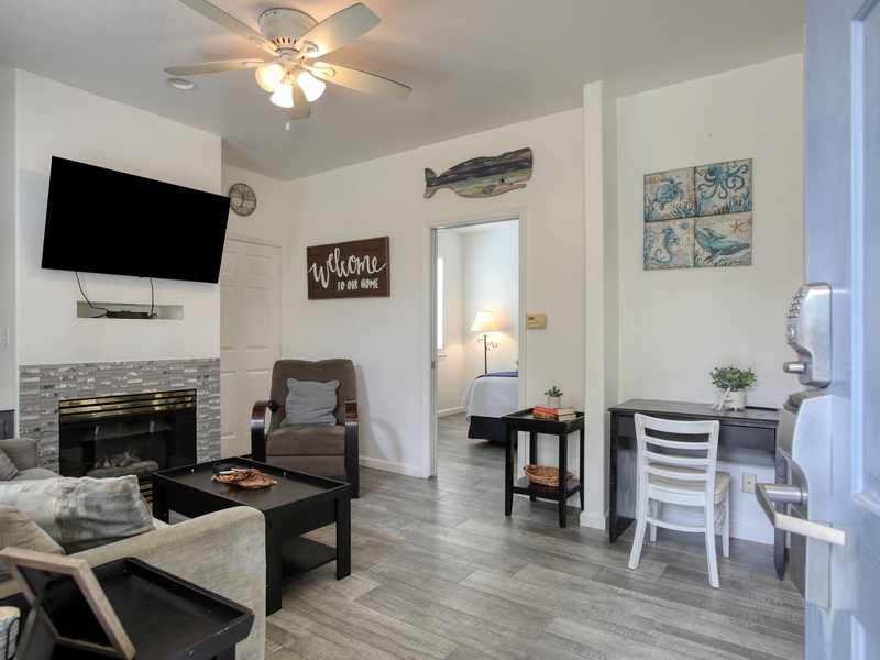 This welcoming living area includes a cozy fireplace, comfortable seating, and a small workspace with direct access to the bedroom.
