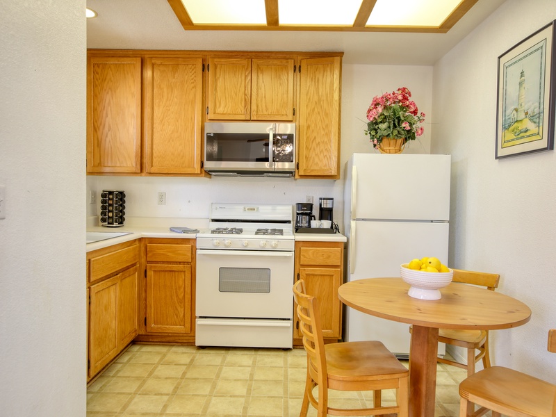This modern kitchen features oak cabinets for storage, a gas stove and a cozy dining nook for three.