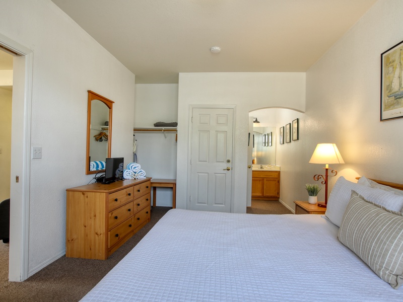 This inviting bedroom offers a comfortable king bed, calming coastal décor, a spacious dresser and bright natural light for a relaxing retreat.