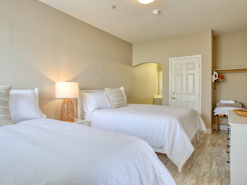 The bedroom features two queen beds with Tuft & Needle mattresses, dressed in luxurious, high-quality linens from The Comphy Company, plus a dresser for convenient clothing storage.