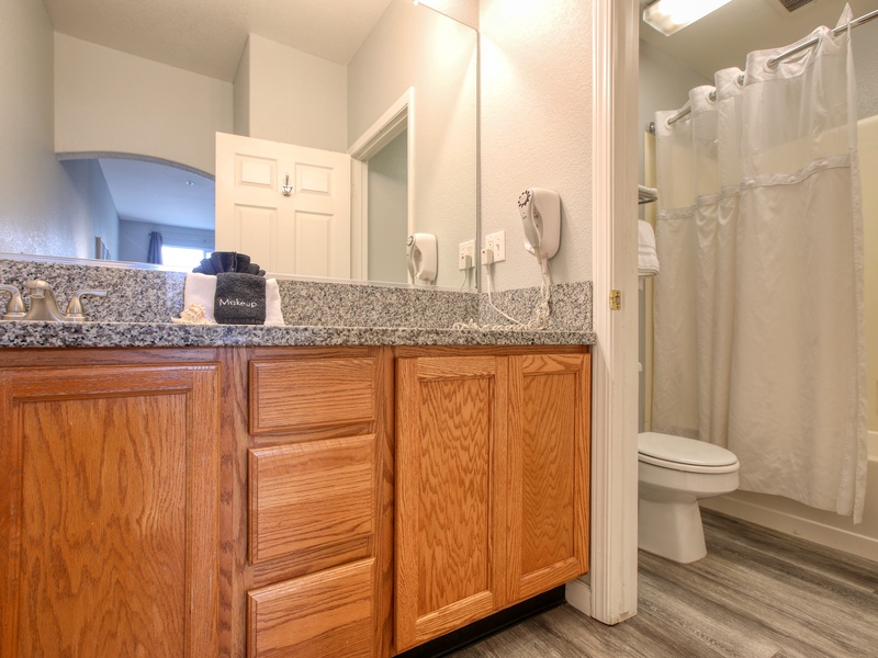 This bathroom features a spacious vanity with ample storage, a large mirror, upgraded countertops and a shower-tub combination for convenience.