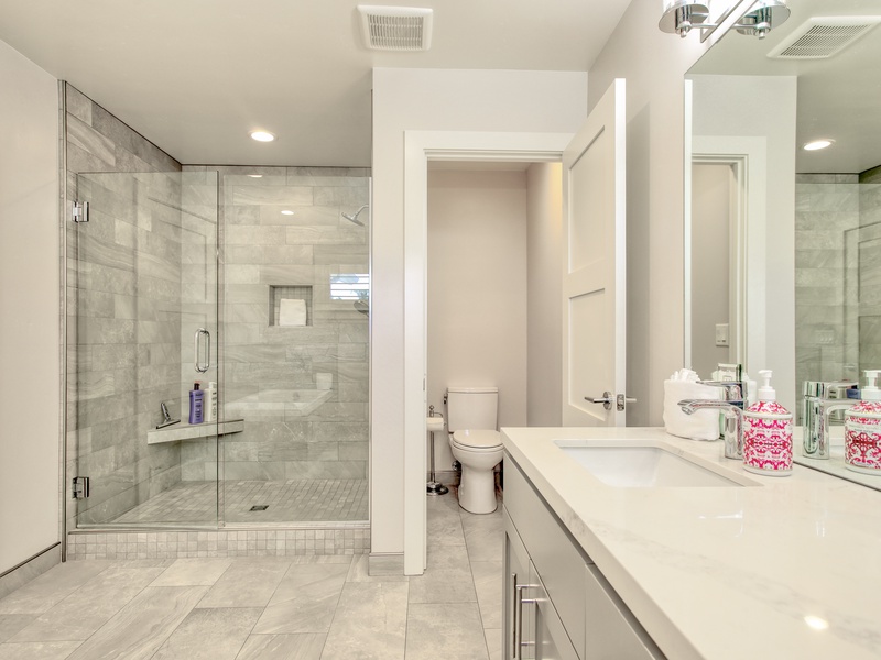 The master bathroom is a serene retreat featuring a spacious walk-in shower with sleek glass doors and elegant tilework that invites you to refresh after a day in the sun. 