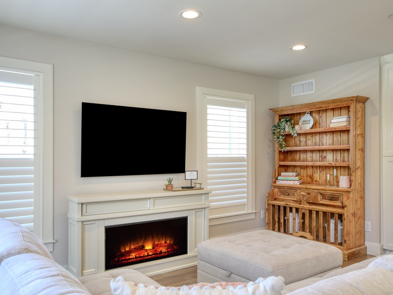 A charming faux fireplace adds a warm, cozy ambiance, making this space feel like home after a day of coastal adventures.