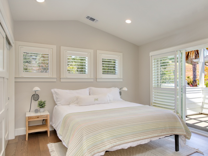 Also on the second floor is a bright, sunlit bedroom furnished with a cozy queen bed and direct access to a private balcony — perfect for enjoying the fresh air and coastal views.