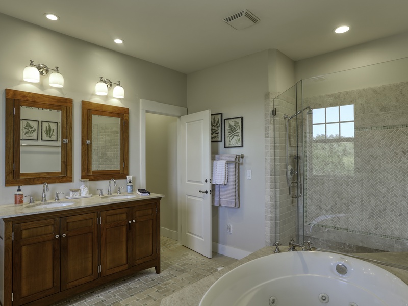 The luxurious primary ensuite bathroom is designed for indulgence, featuring a soothing jetted tub, a convenient double vanity, and a spacious walk-in shower. This area also provides additional storage within the large walk-in closet.