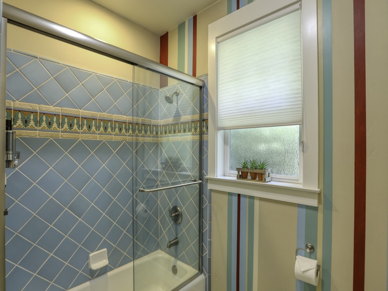 The tub/shower combo in this full bathroom is part of a bright, cheerful space designed to refresh and uplift.