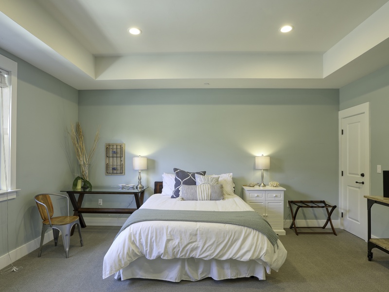 Fifth Bedroom Jr. Suite: This spacious, street-level Jr. Suite is designed in a calming coastal palette and theme. It features a comfortable Queen bed with fluffy white linens and a dedicated sitting area. The room’s generous size easily accommodates a pack 'n play or an extra twin roll-out bed for flexible sleeping arrangements. 
