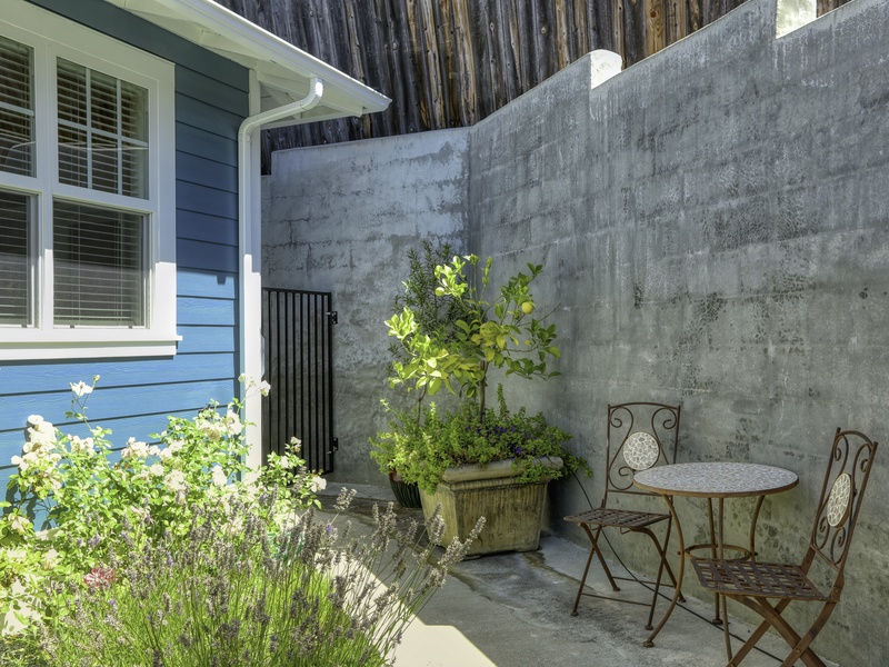 Just near the entry, discover a charming, private garden nook. This secluded space features a bistro table and chairs—the perfect spot for enjoying a quiet morning coffee or an evening drink amidst the greenery.